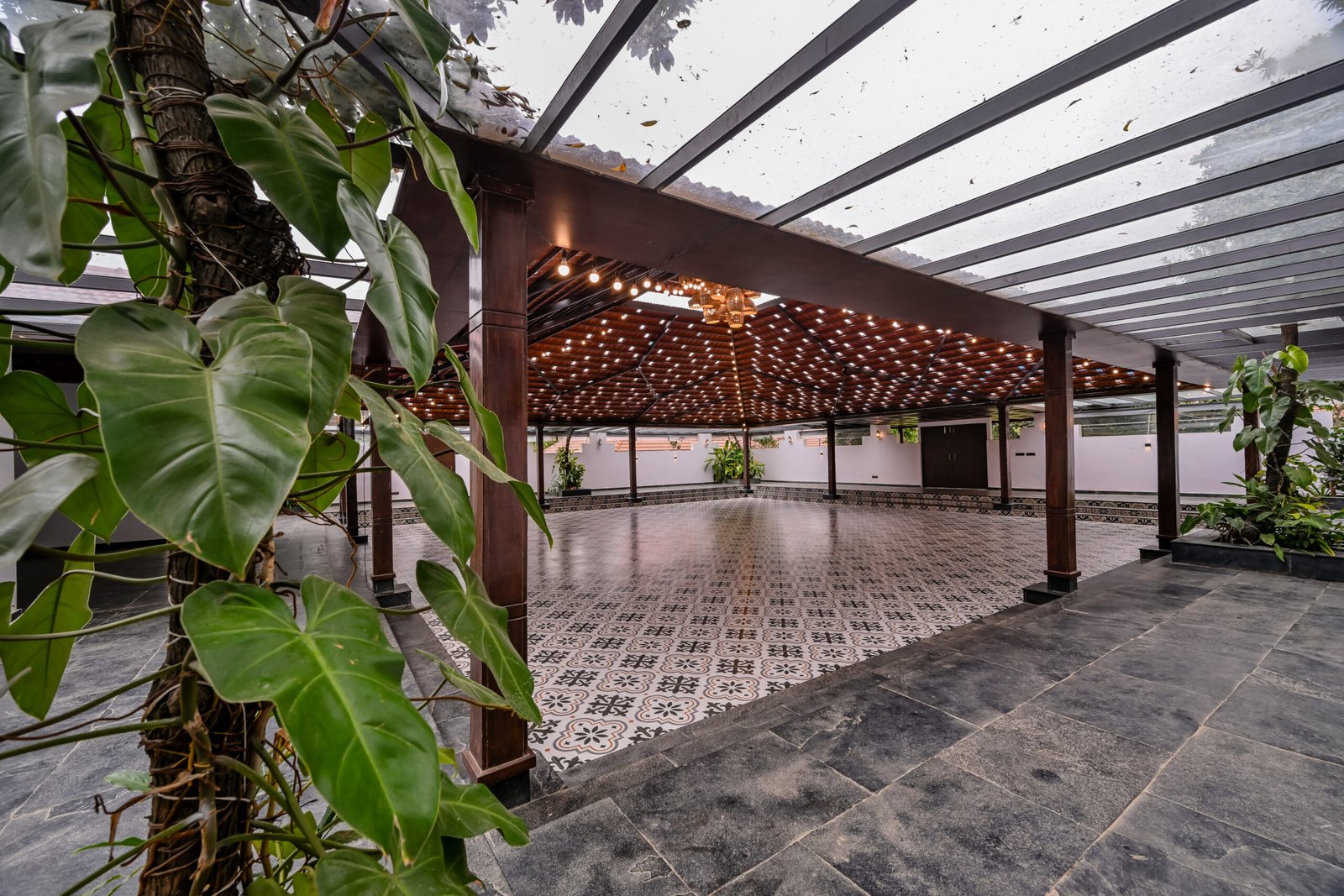 Covered outdoor wedding area with wooden pavilion, patterned flooring and greenery at The Lily Pond in East Bangalore
